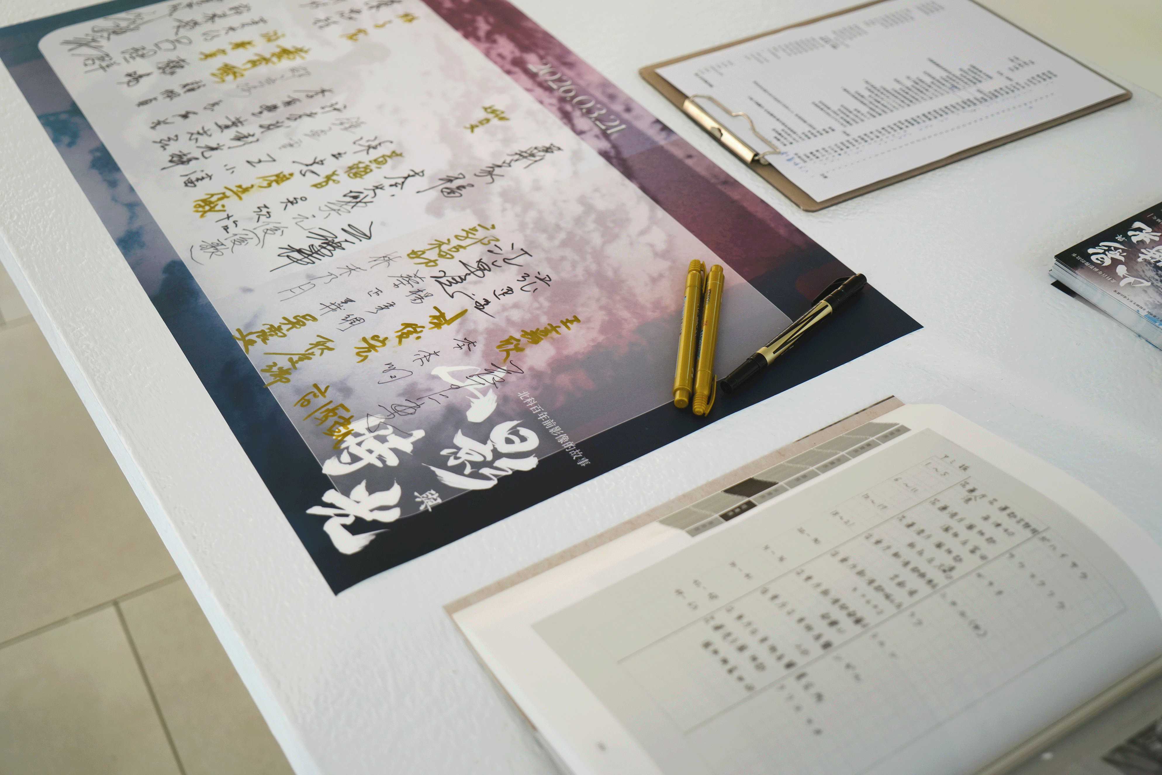 簽到桌上擺放的展覽主視覺簽名海報與簽字筆。